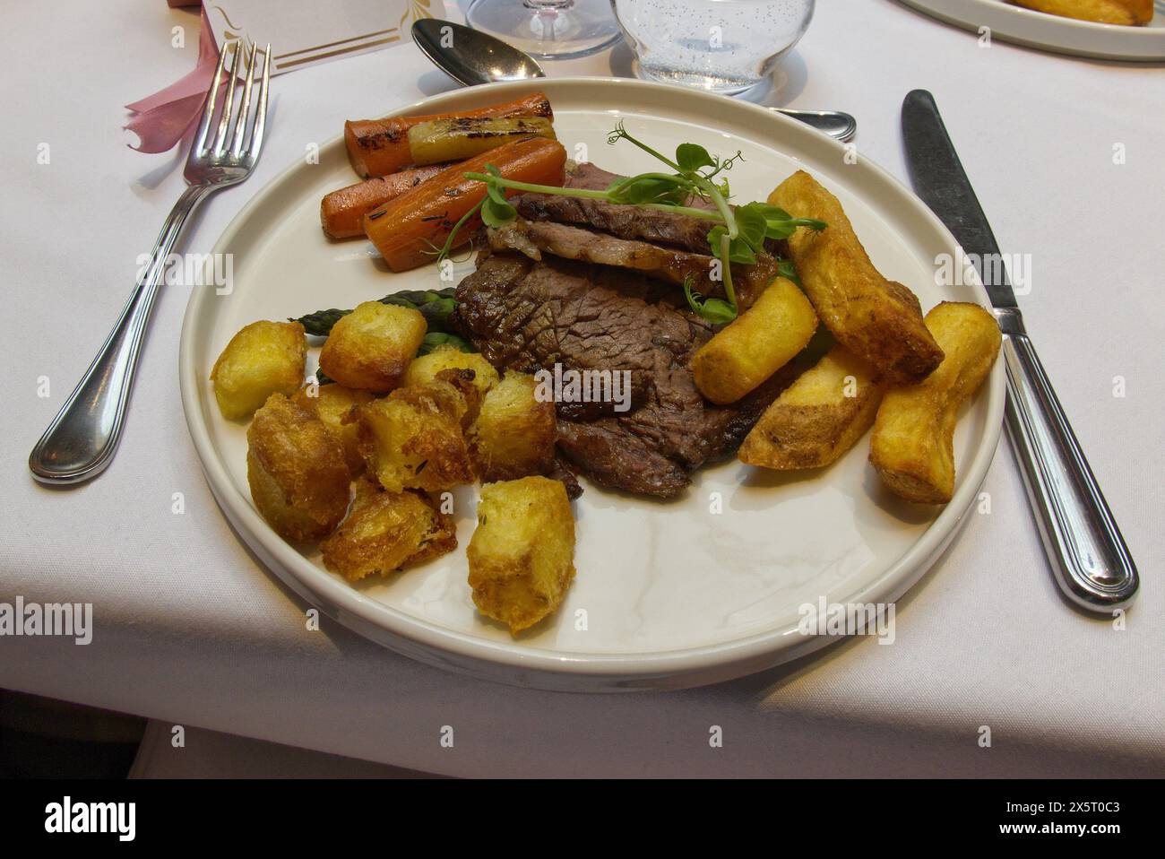 Im Restaurant gab es Roastbeef mit Karotten, Spargel, Bratkartoffeln und Pommes frites Stockfoto