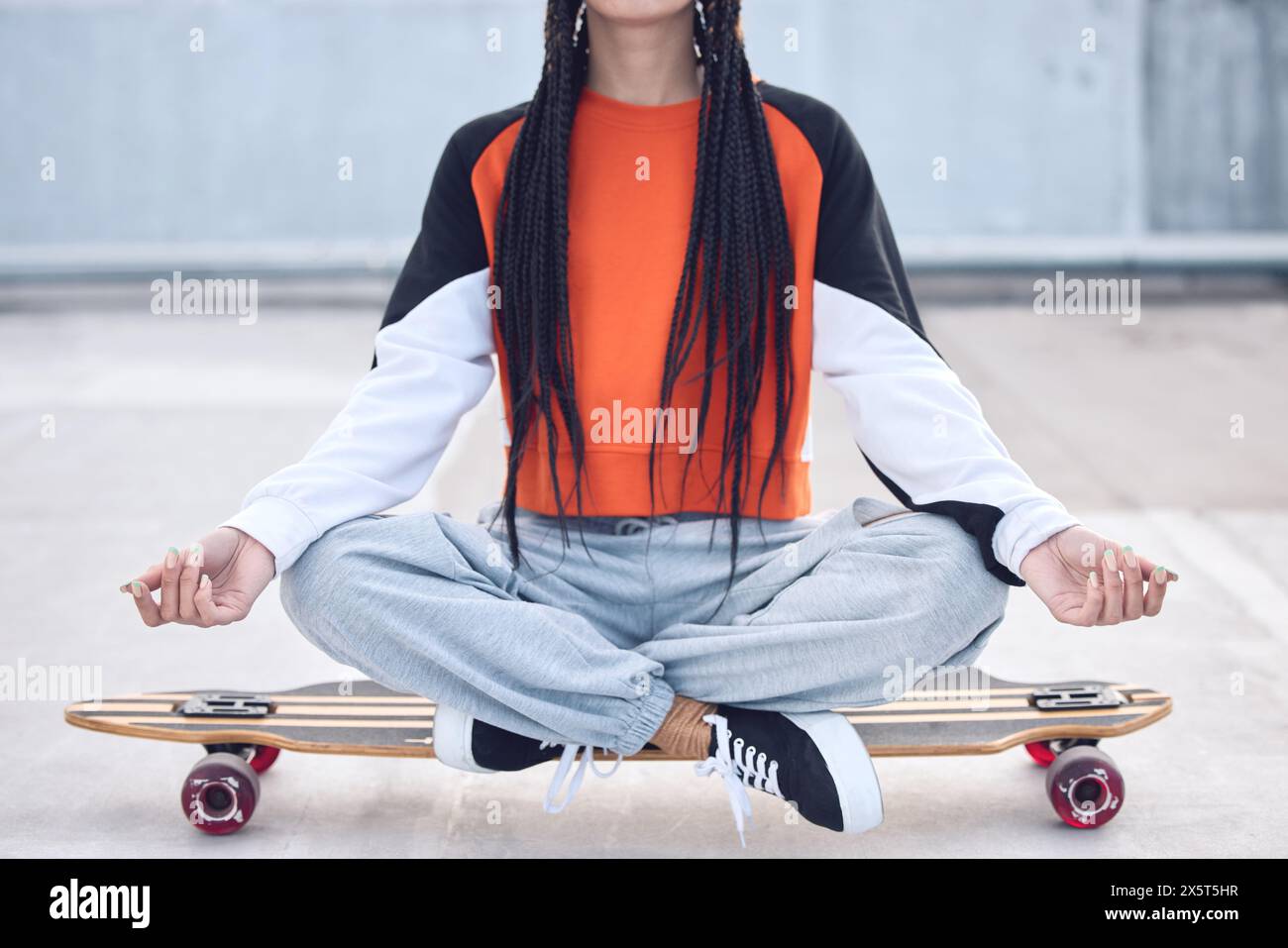 Meditieren Sie, entspannen Sie und lassen Sie sich auf Skateboard im Freien frei – mit Streetwear, Ruhe und Betonboden. Gen z Girl, Lotus Pose und Longboard zur Ruhe Stockfoto