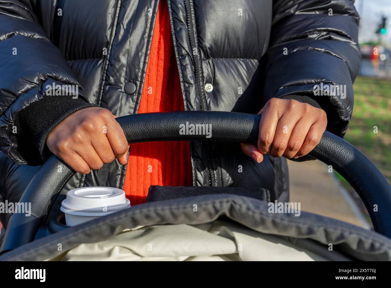 Frau schiebt Kinderwagen im Park Stockfoto