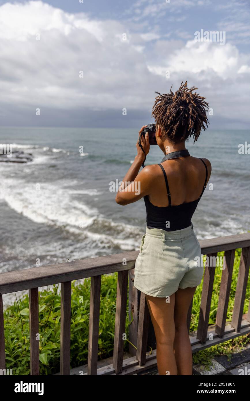 Indonesien, Bali, weibliche Touristen fotografieren Meer vom Beobachtungspunkt Stockfoto