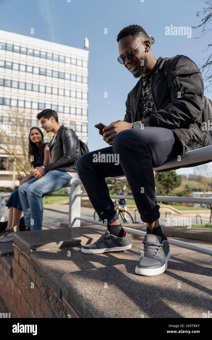 Eine Gruppe von Studenten sitzt auf der Bank auf dem Campus Stockfoto