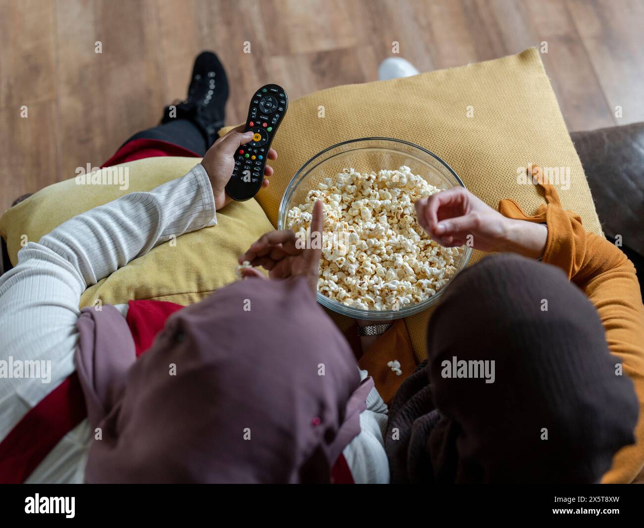Blick auf Freunde, die auf dem Sofa sitzen und Popcorn essen Stockfoto