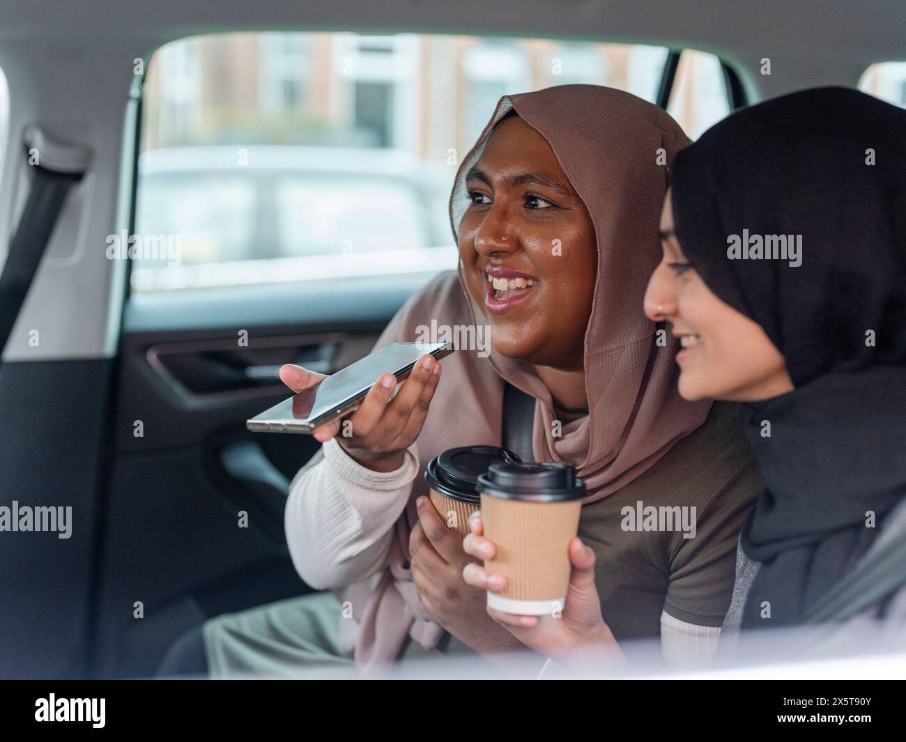 Frauen, die im Auto sitzen und telefonieren Stockfoto