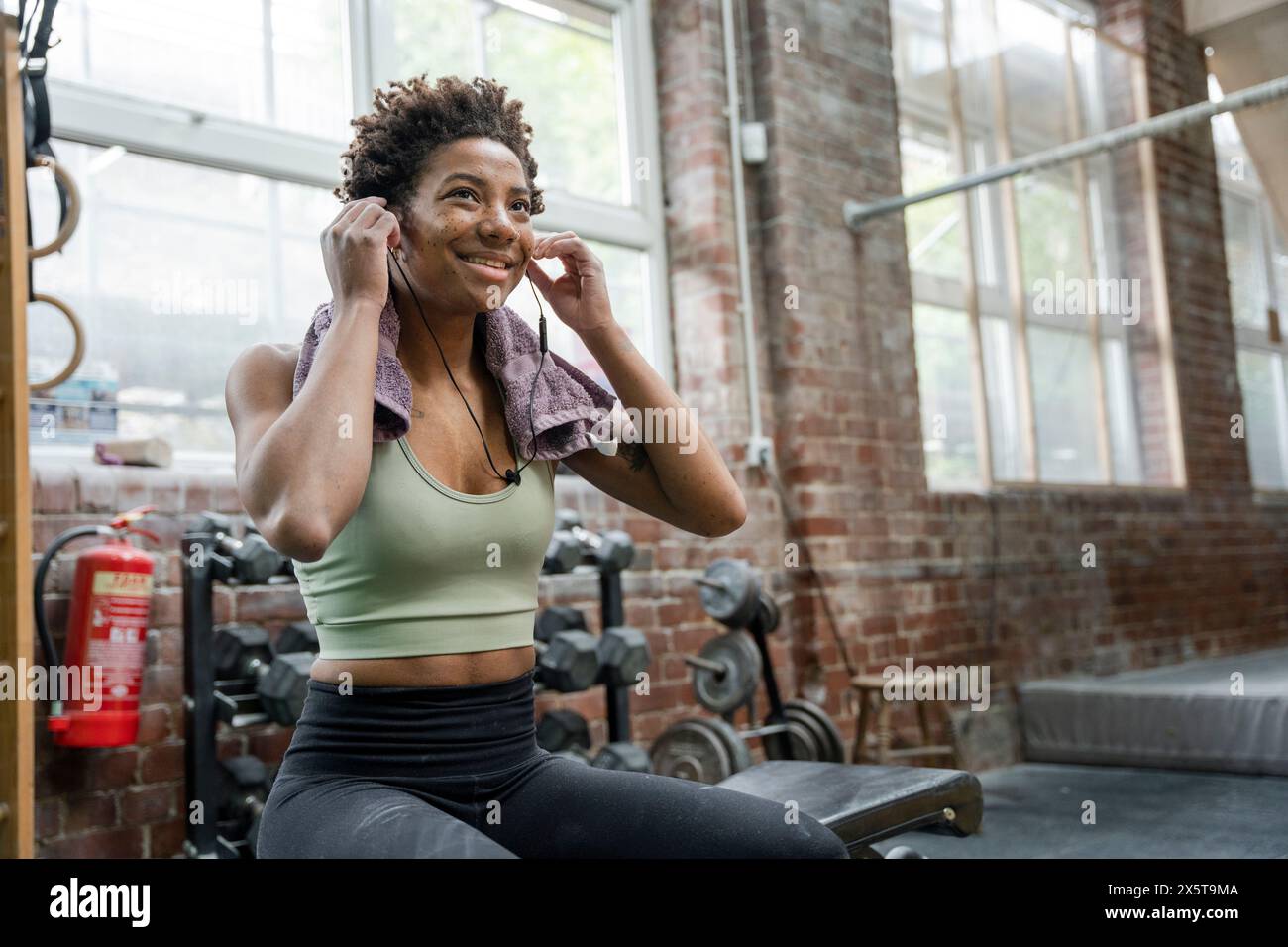 Frau, die während des Trainings im Fitnessstudio Kopfhörer aufsetzt Stockfoto