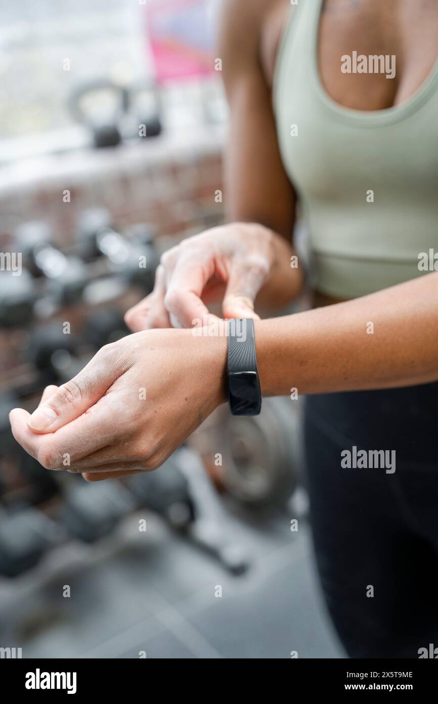 Frau, die im Fitnessstudio Fitness-Tracker zur Hand hat Stockfoto