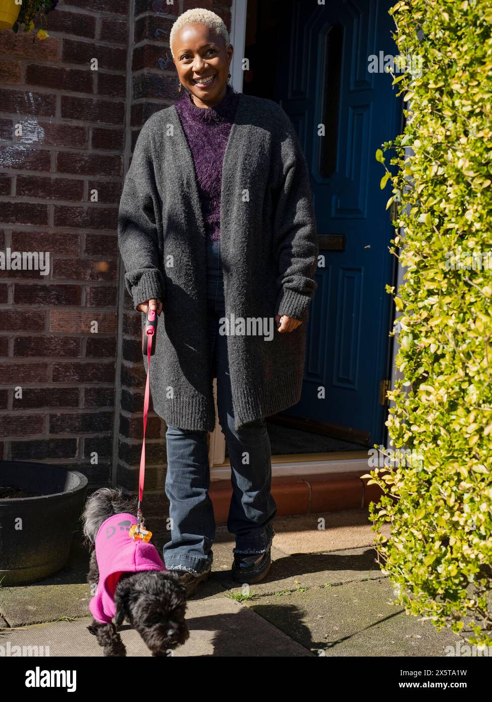 Lächelnde Frau, die mit einem Hund an der Leine läuft Stockfoto