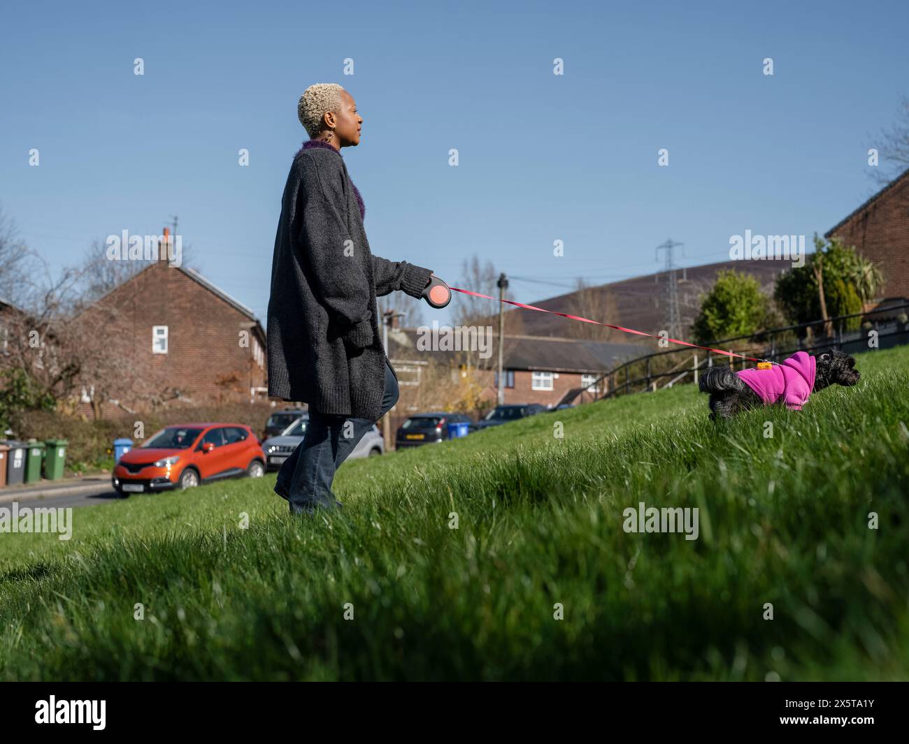 Frau, die mit Hund an der Leine im Wohnviertel läuft Stockfoto