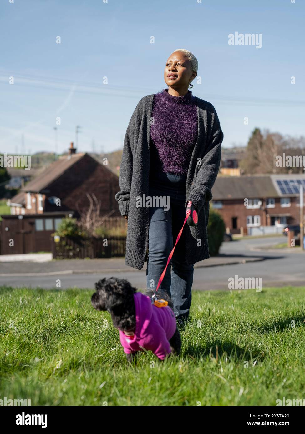 Frau, die mit Hund an der Leine im Wohnviertel läuft Stockfoto