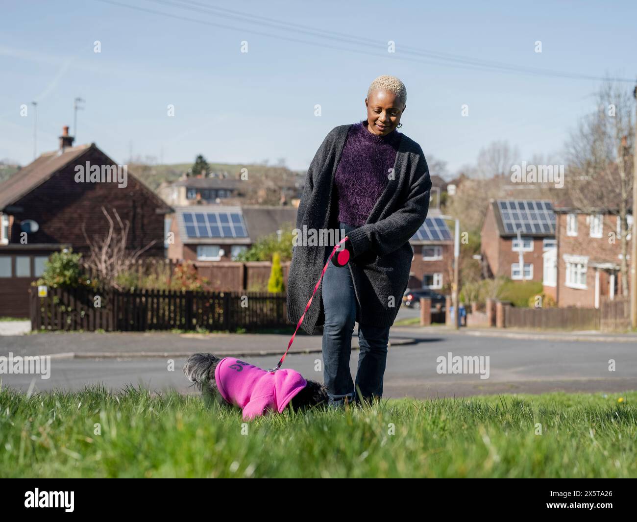 Frau, die mit Hund an der Leine im Wohnviertel läuft Stockfoto