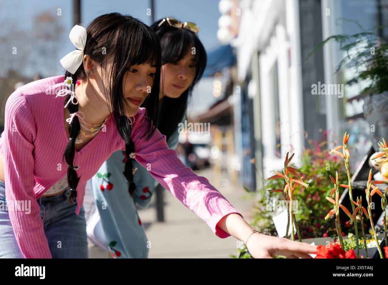 Junge Freundinnen, die Blumen kaufen Stockfoto