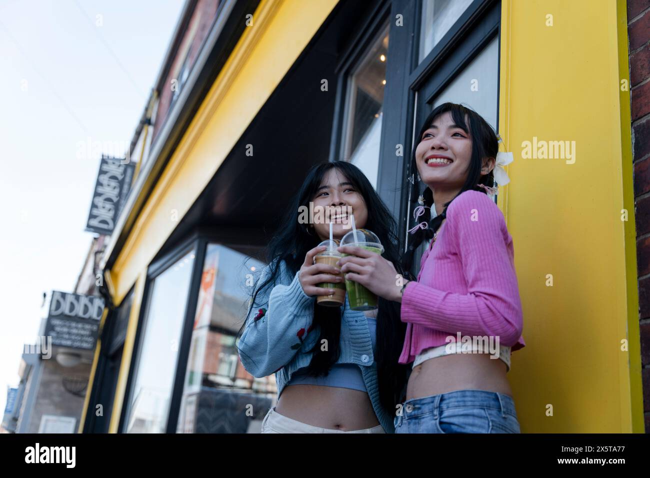 Junge Frauen stehen vor dem Gebäude mit süßen Getränken Stockfoto