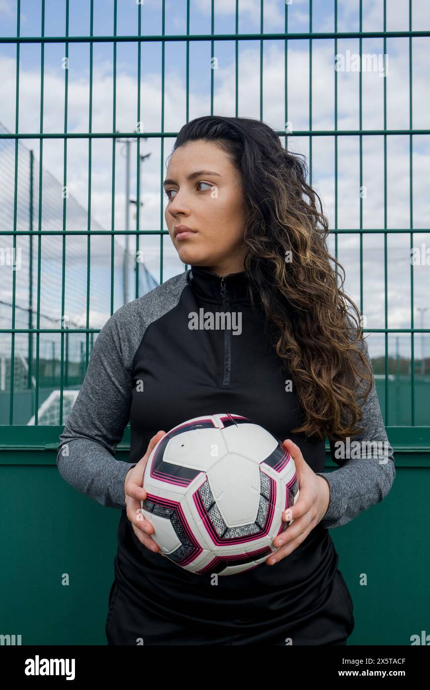 Eine junge Frau, die draußen Fußball hält Stockfoto