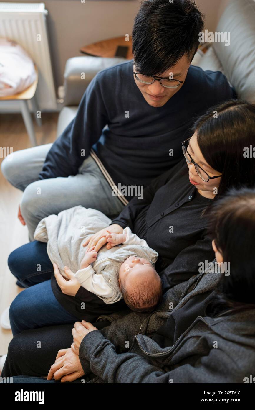 Familie in zwei Generationen mit Baby (0-1 Monate), das auf dem Sofa sitzt Stockfoto