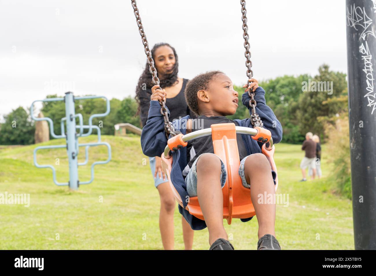 Mutter schwingender Sohn auf dem Spielplatz Stockfoto