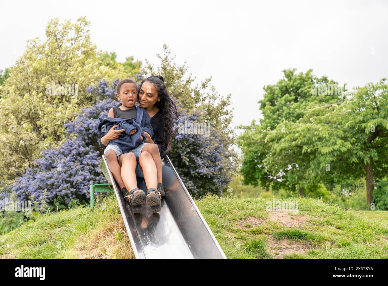 Mutter und Sohn haben Spaß auf der Rutsche auf dem Spielplatz Stockfoto