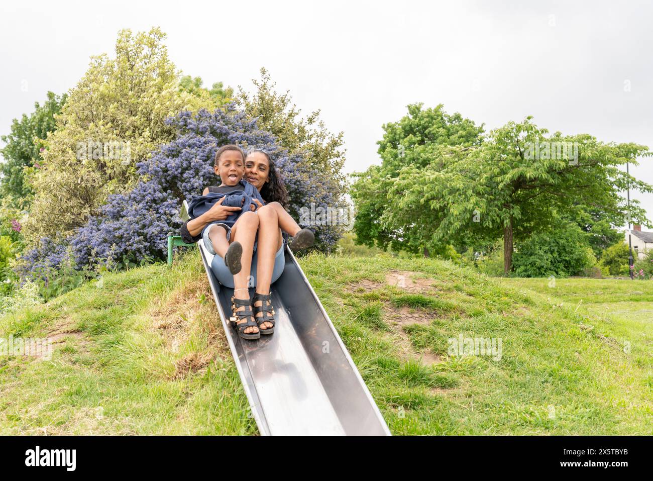 Mutter und Sohn haben Spaß auf der Rutsche auf dem Spielplatz Stockfoto