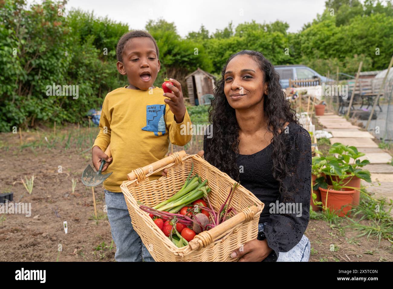 Porträt der Mutter mit Sohn, der einen Korb mit frischem Gemüse hält Stockfoto