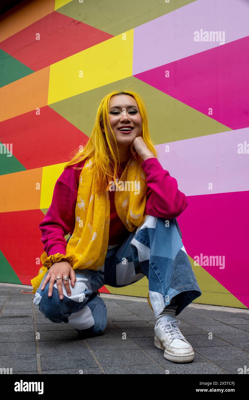Porträt einer jungen Frau mit gelbem Haar, die sich draußen hockt Stockfoto