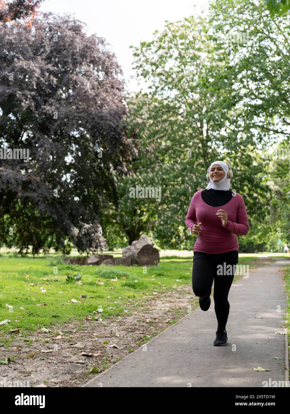 UK, Sutton, Frau im Kopftuch, die im Park joggt Stockfoto