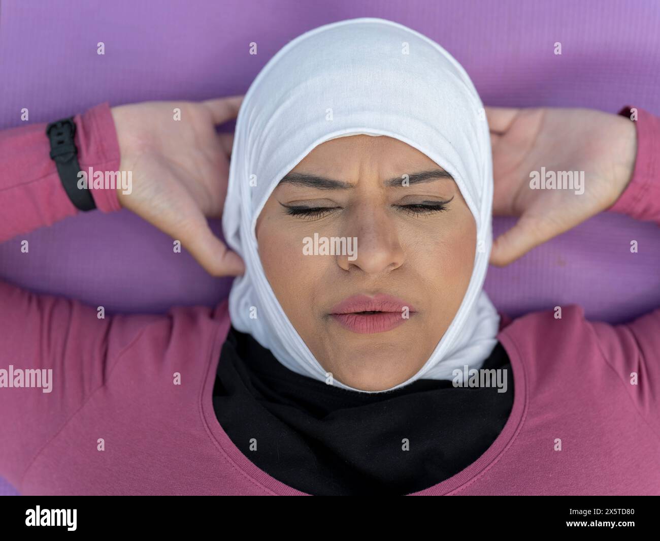 UK, Sutton, Nahaufnahme einer Frau im Kopftuch, die Sit-ups auf Yogamatte macht Stockfoto