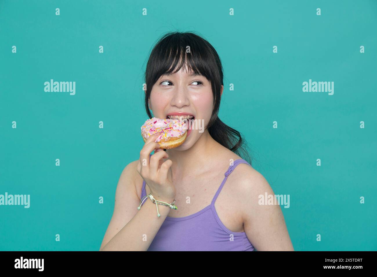 Studio-Porträt eines Mädchens, das Donut isst Stockfoto