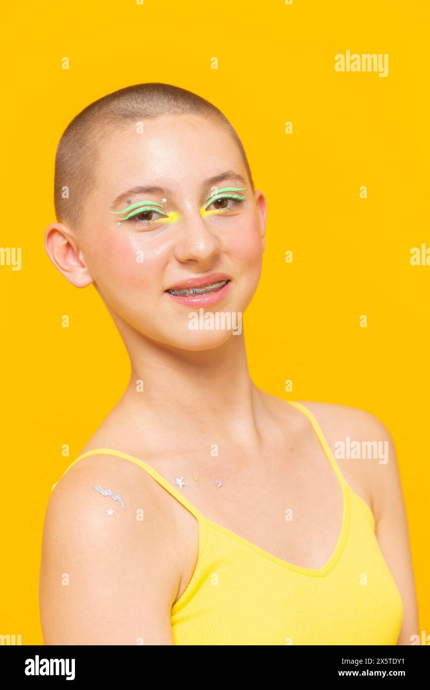 Studio-Porträt eines lächelnden Mädchens mit neonfarbenem Make-up und Sternen auf der Schulter Stockfoto