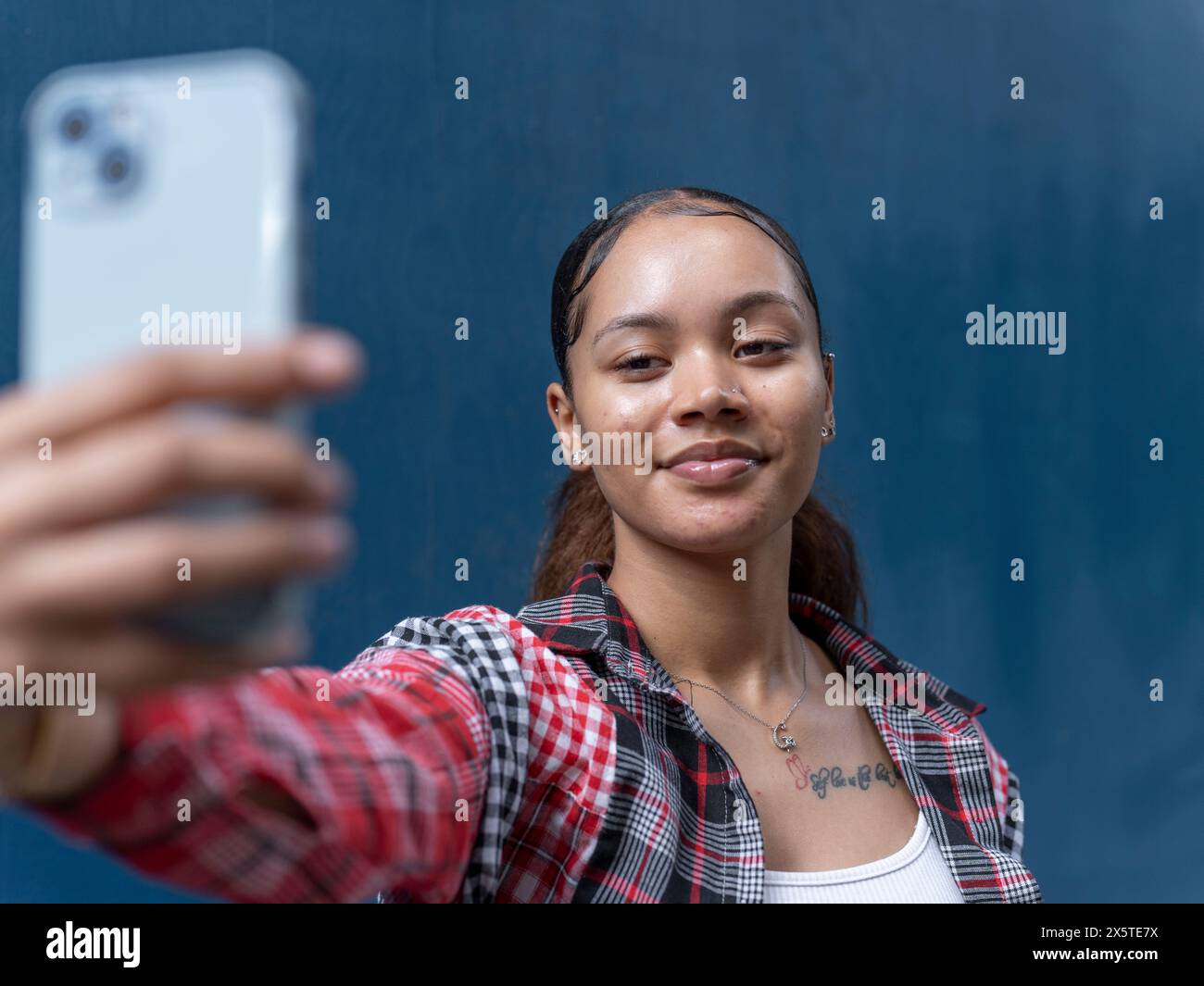 Eine junge Frau macht Selfie gegen die blaue Wand Stockfoto