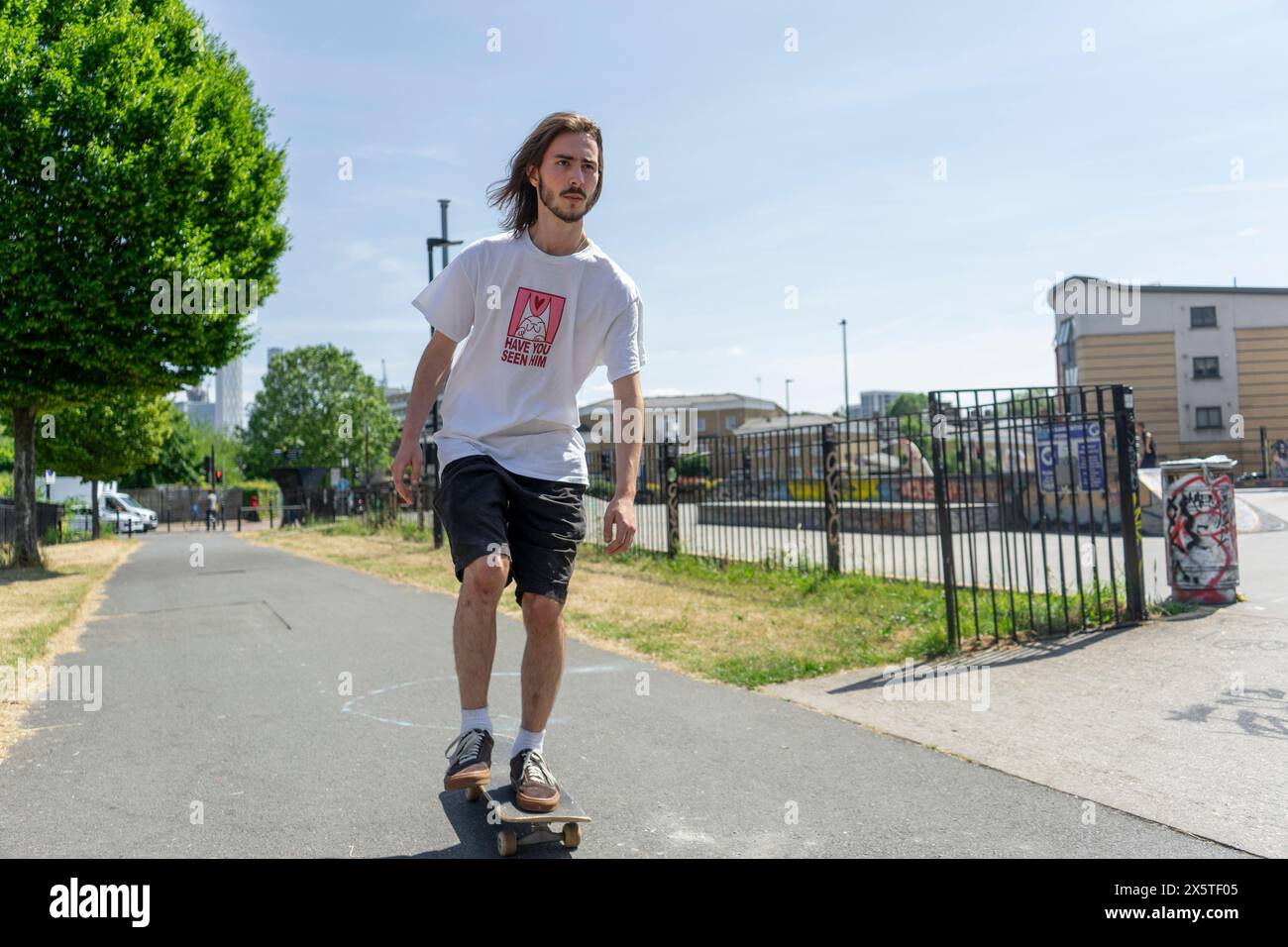 Junger Mann Skateboarding auf Fußpfad Stockfoto