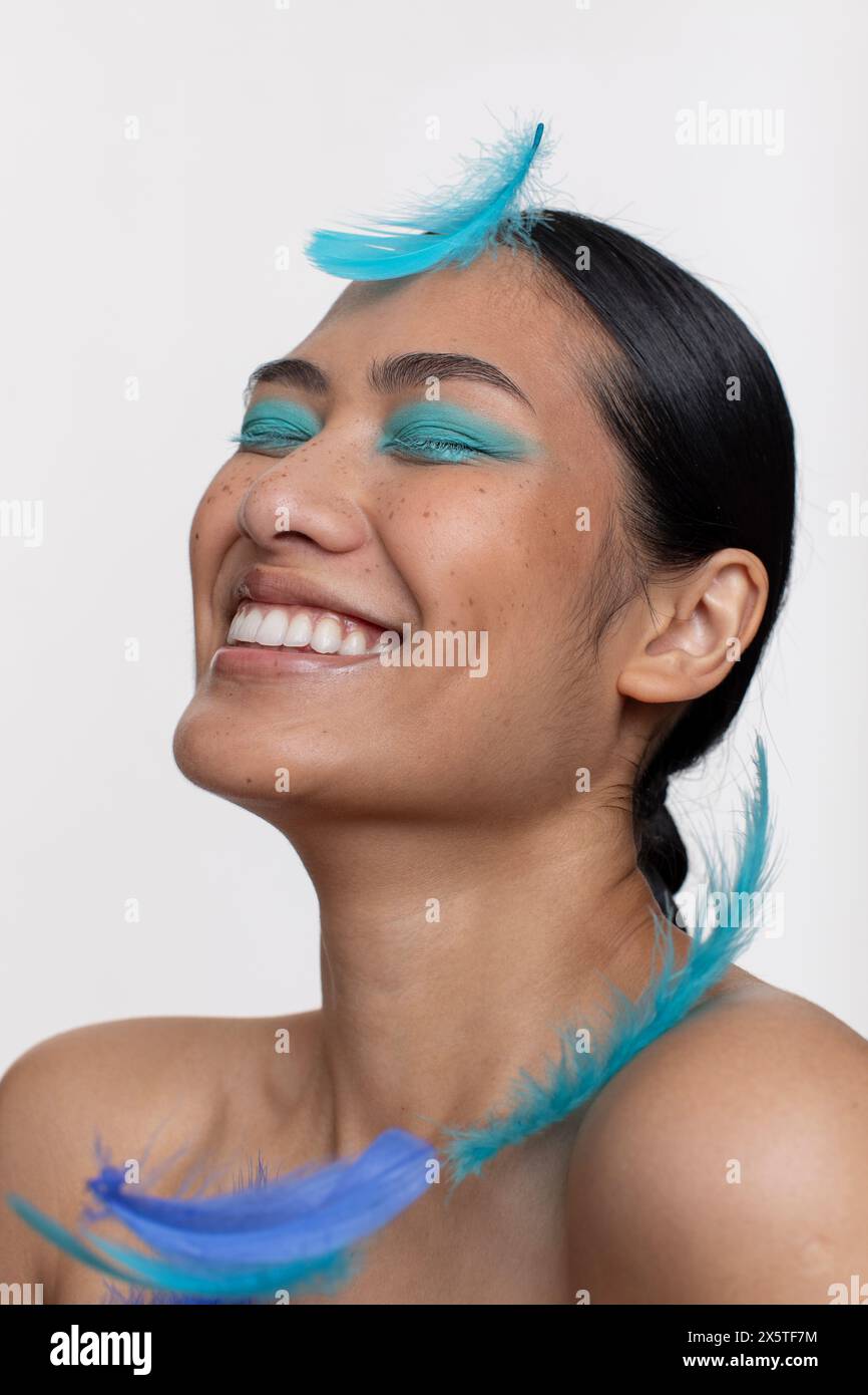 Blaue Federn fallen auf lächelnde Frau Stockfoto