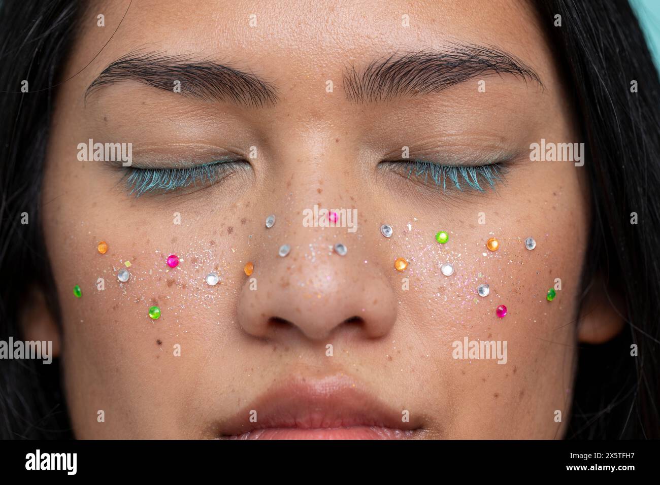 Porträt einer Frau mit geschlossenen Augen mit bunten glänzenden Sommersprossen Stockfoto