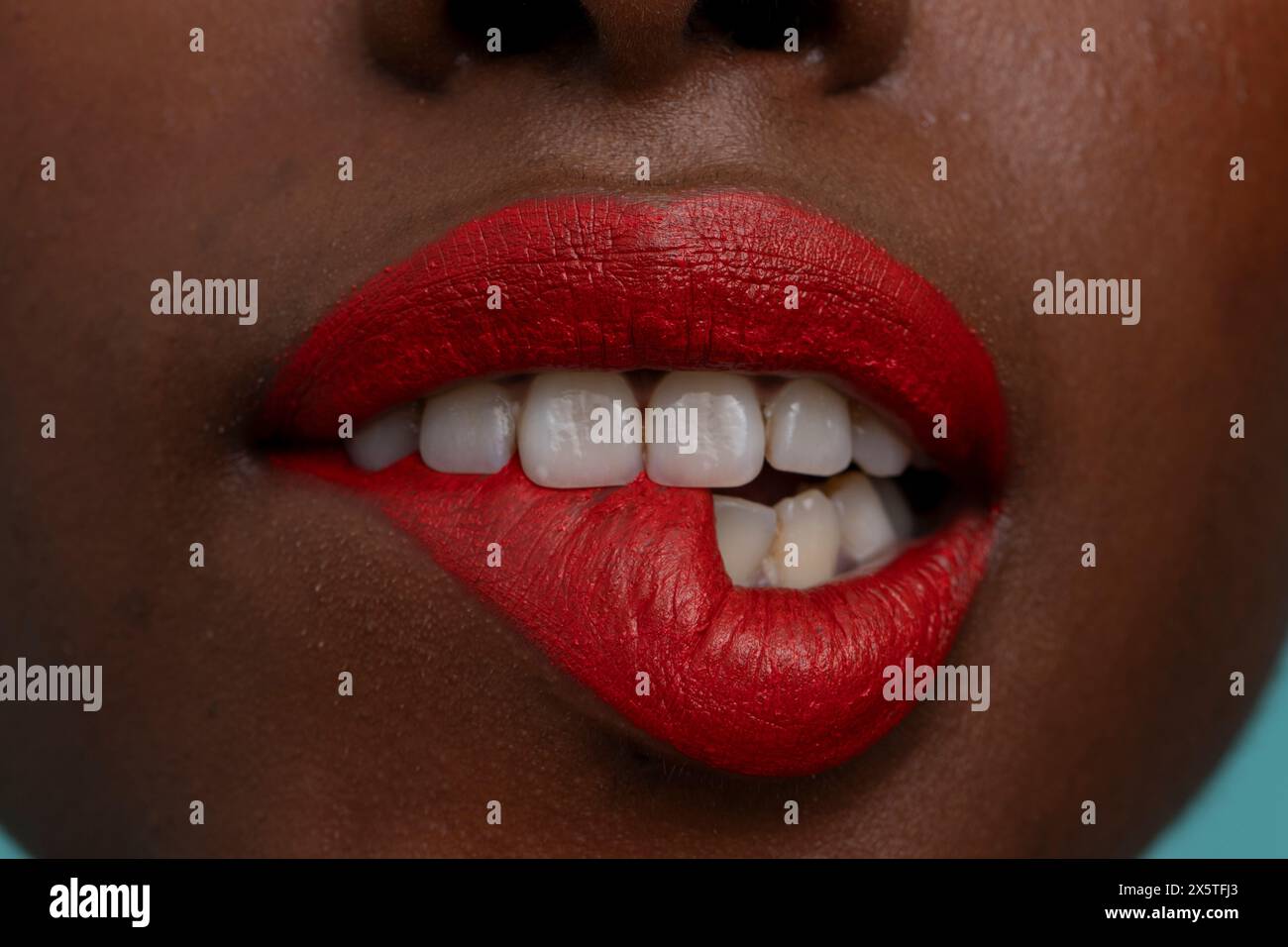 Frau trägt roten Lippenstift, beißt auf die Lippe Stockfoto