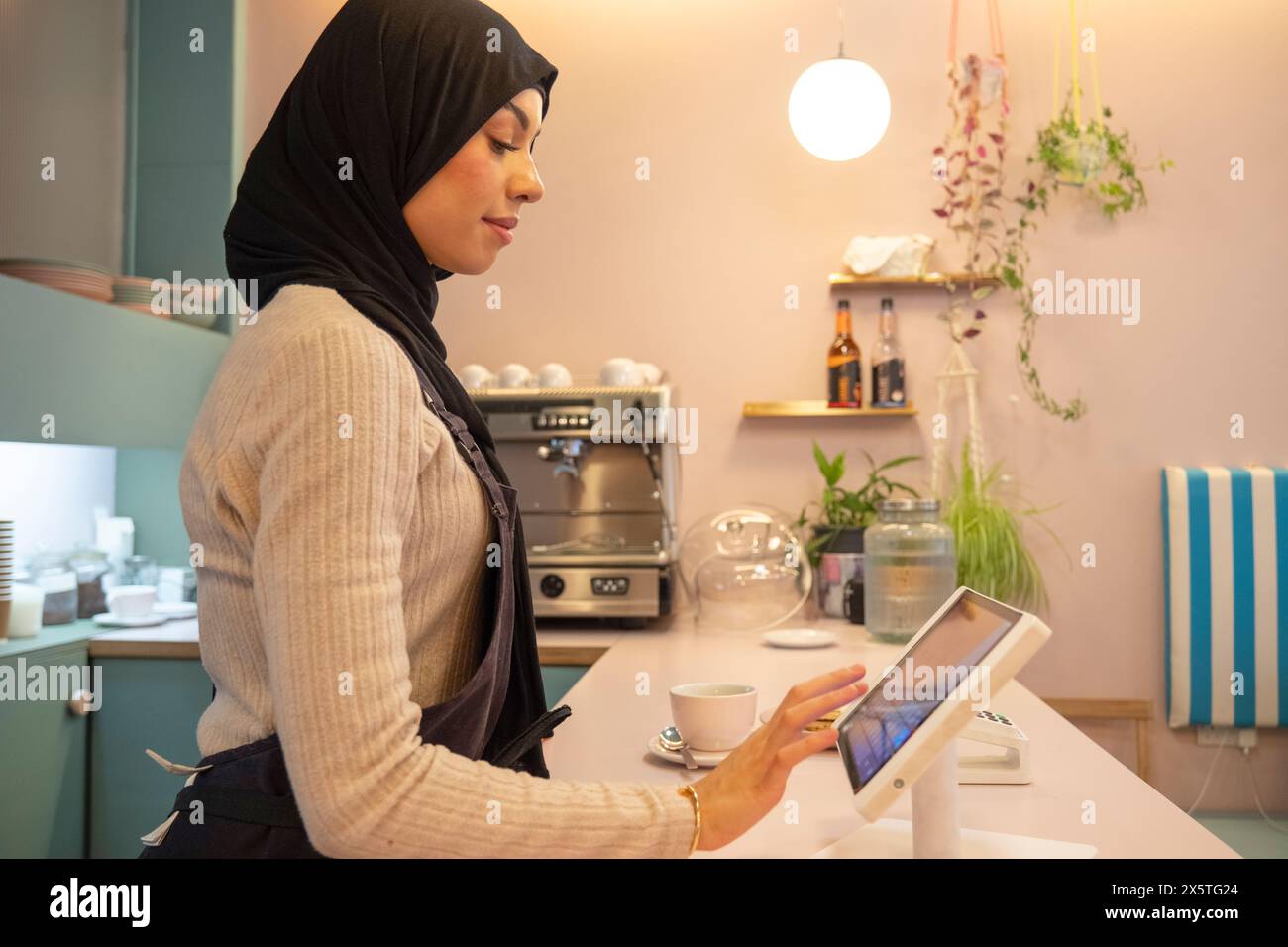 Junge Frau im Hijab, die im Café arbeitet Stockfoto