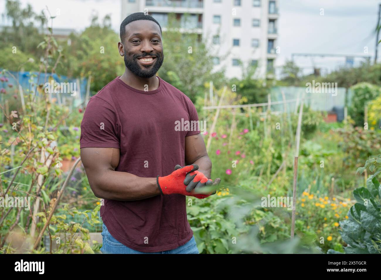 Porträt eines lächelnden Mannes, der im städtischen Gemüsegarten steht Stockfoto