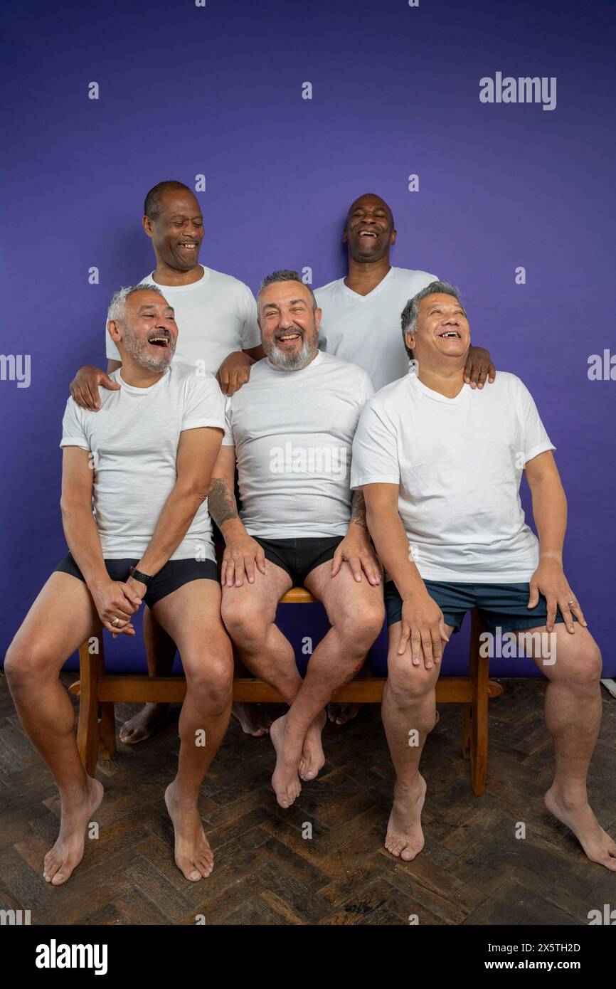 Porträt von älteren Männern, die vor violettem Hintergrund lachen Stockfoto