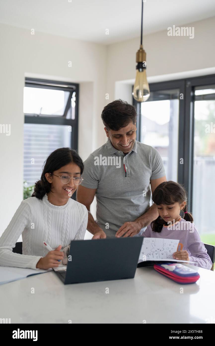 Vater hilft Töchtern bei Hausaufgaben Stockfoto