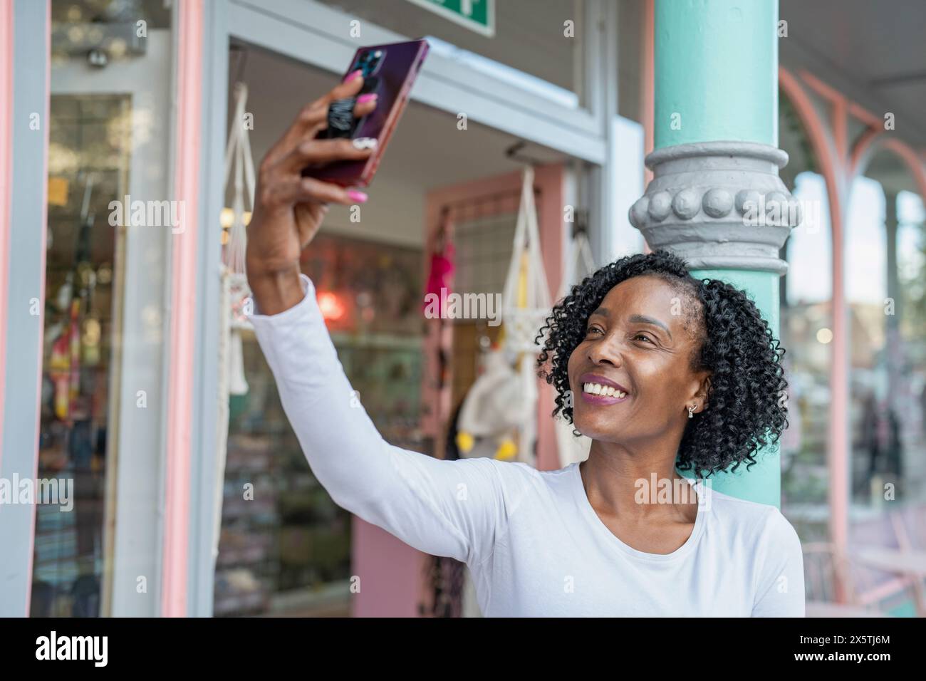 Lächelnde Frau macht Selfie vor dem Gebäude Stockfoto