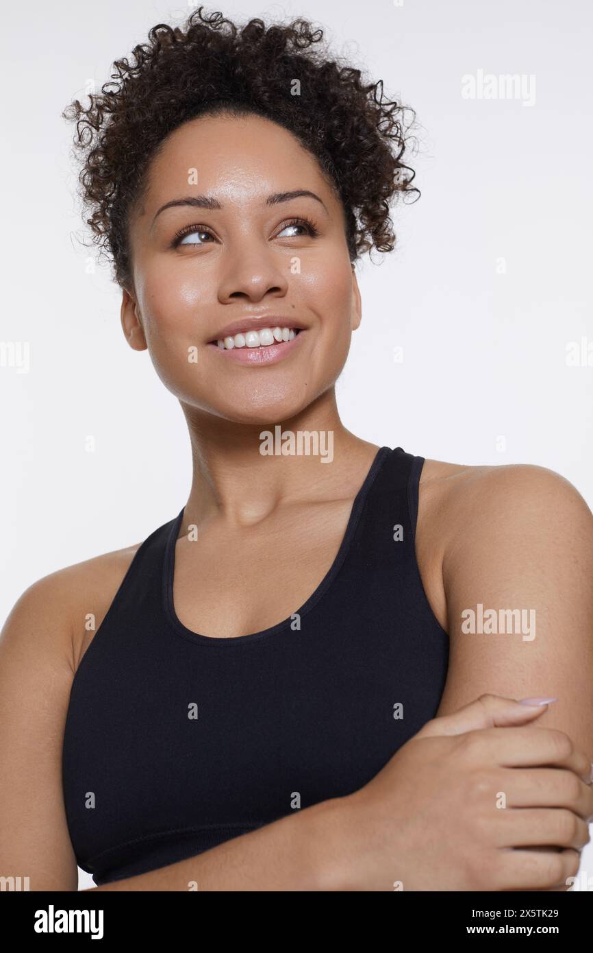 Studio-Porträt einer lächelnden Sportfrau in schwarzem Oberteil Stockfoto