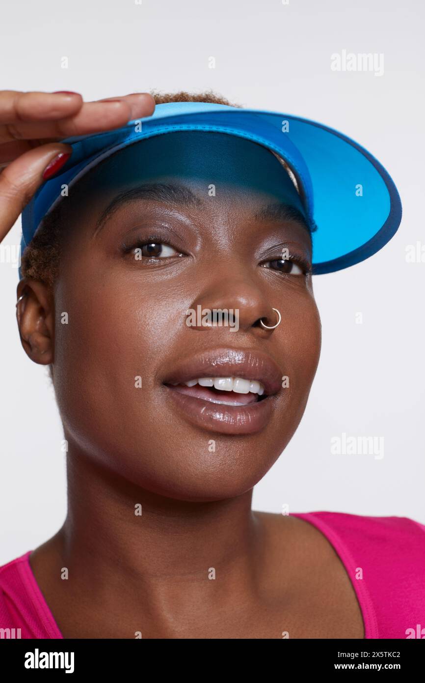 Studio-Porträt einer lächelnden Frau mit blauer Sonnenblende Stockfoto
