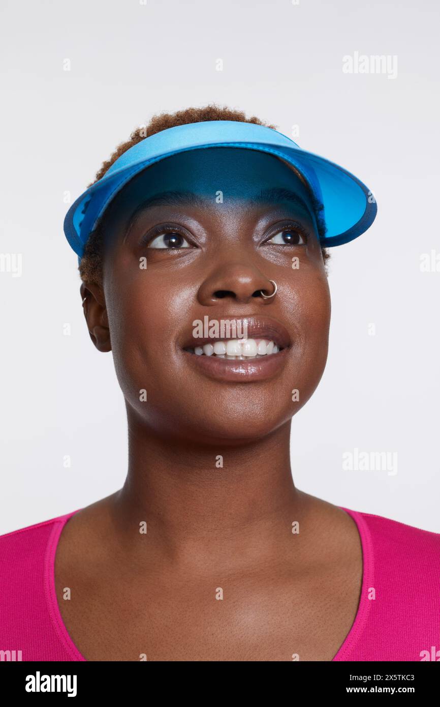 Studio-Porträt einer lächelnden Frau mit blauer Sonnenblende Stockfoto