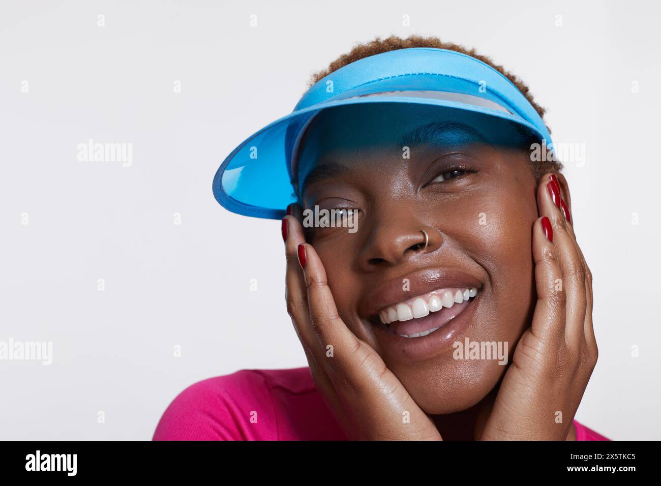 Studio-Porträt einer lächelnden Frau mit blauer Sonnenblende Stockfoto