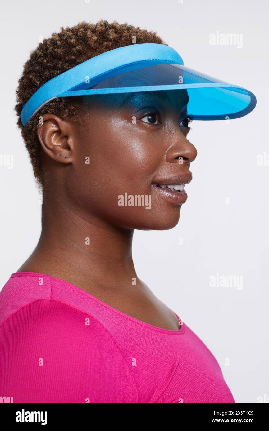 Profil einer lächelnden Frau mit blauer Sonnenblende und rosa Hemd Stockfoto