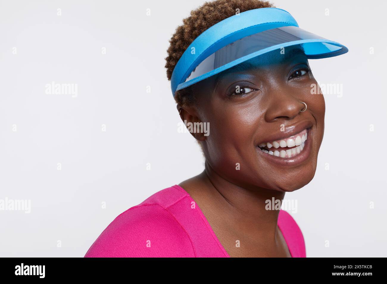 Studio-Porträt einer lächelnden Frau mit blauer Sonnenblende Stockfoto