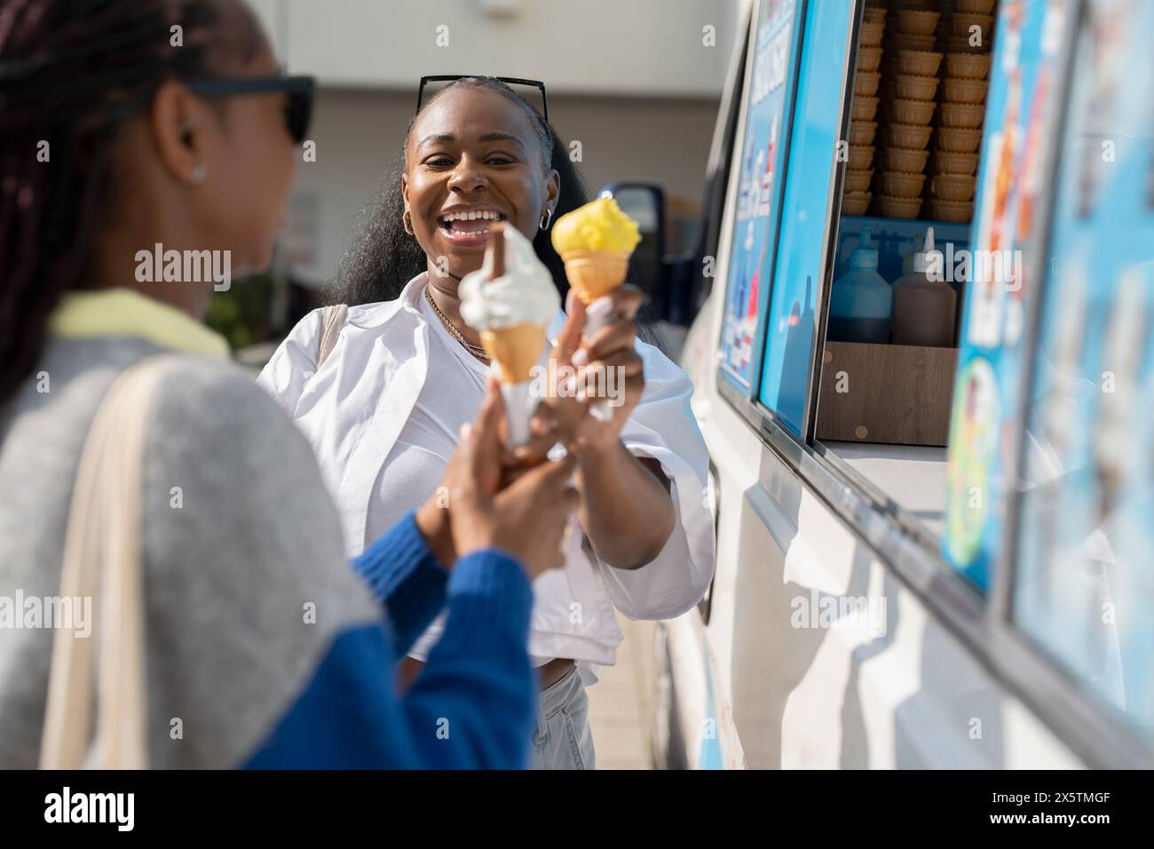 Junge Freundinnen, die Eis im Eiswagen kaufen Stockfoto