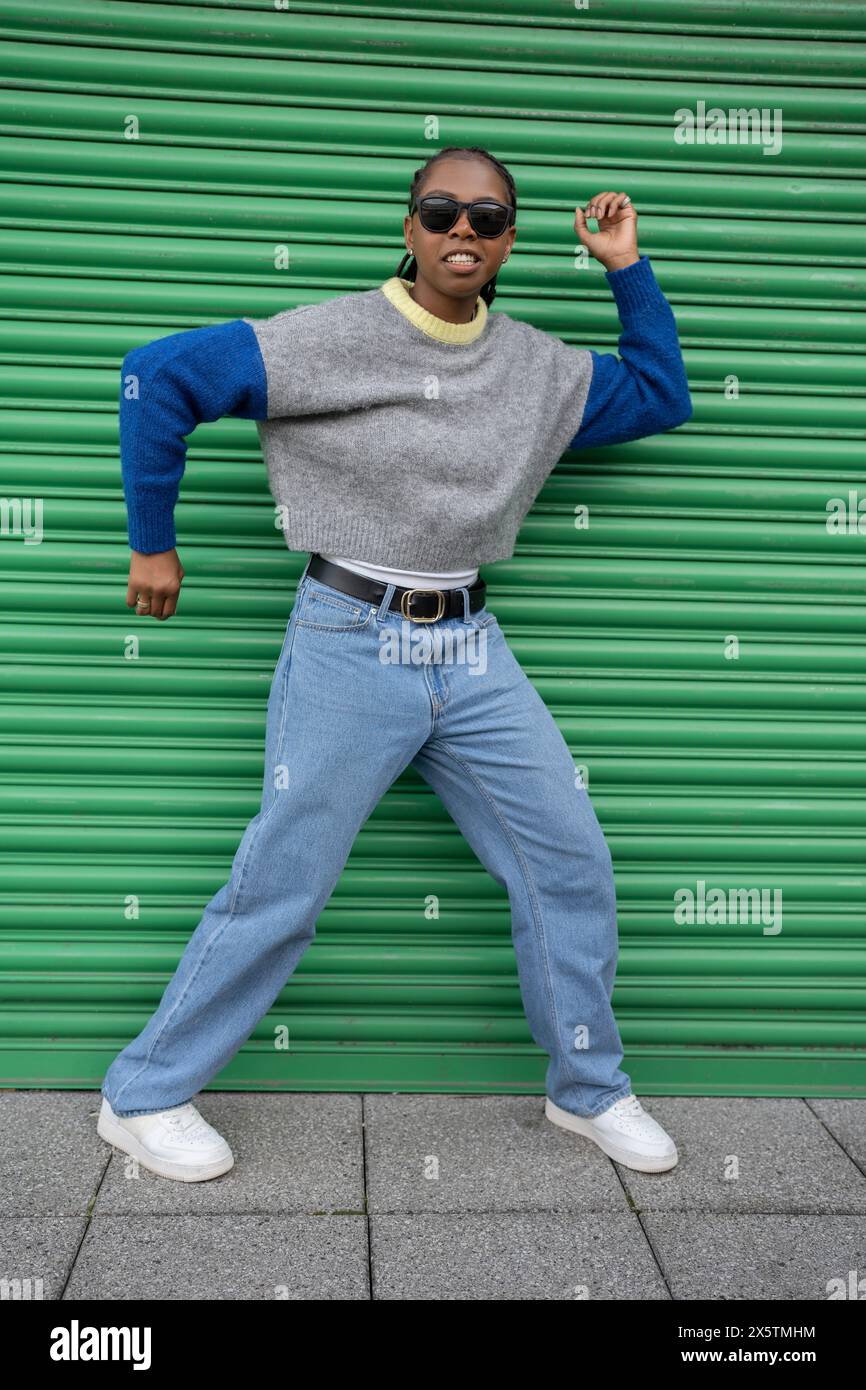Eine junge, stilvolle Frau, die tanzt, posiert vor der grünen Tür Stockfoto
