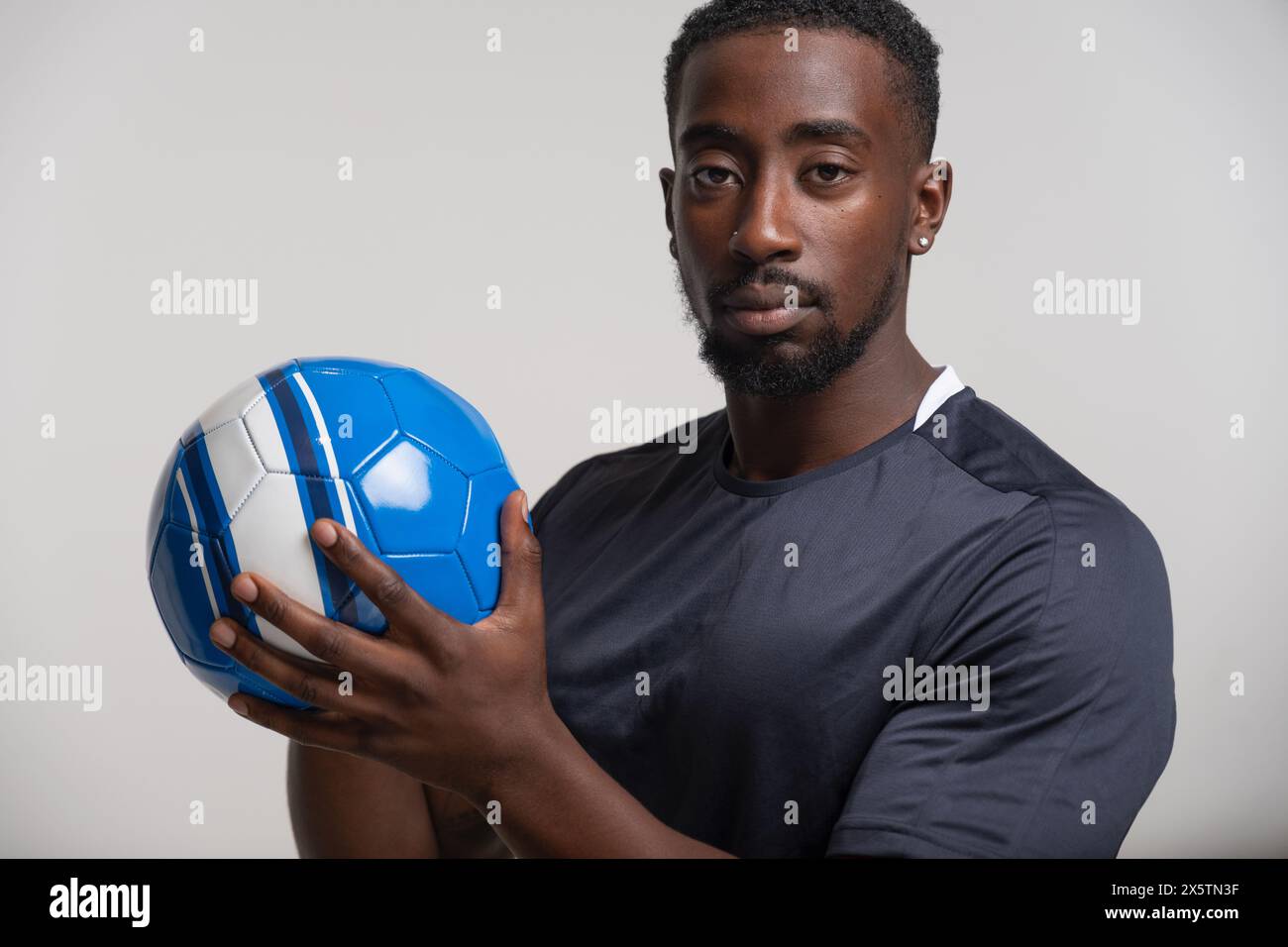 Porträt eines Mannes, der Volleyballball hält Stockfoto