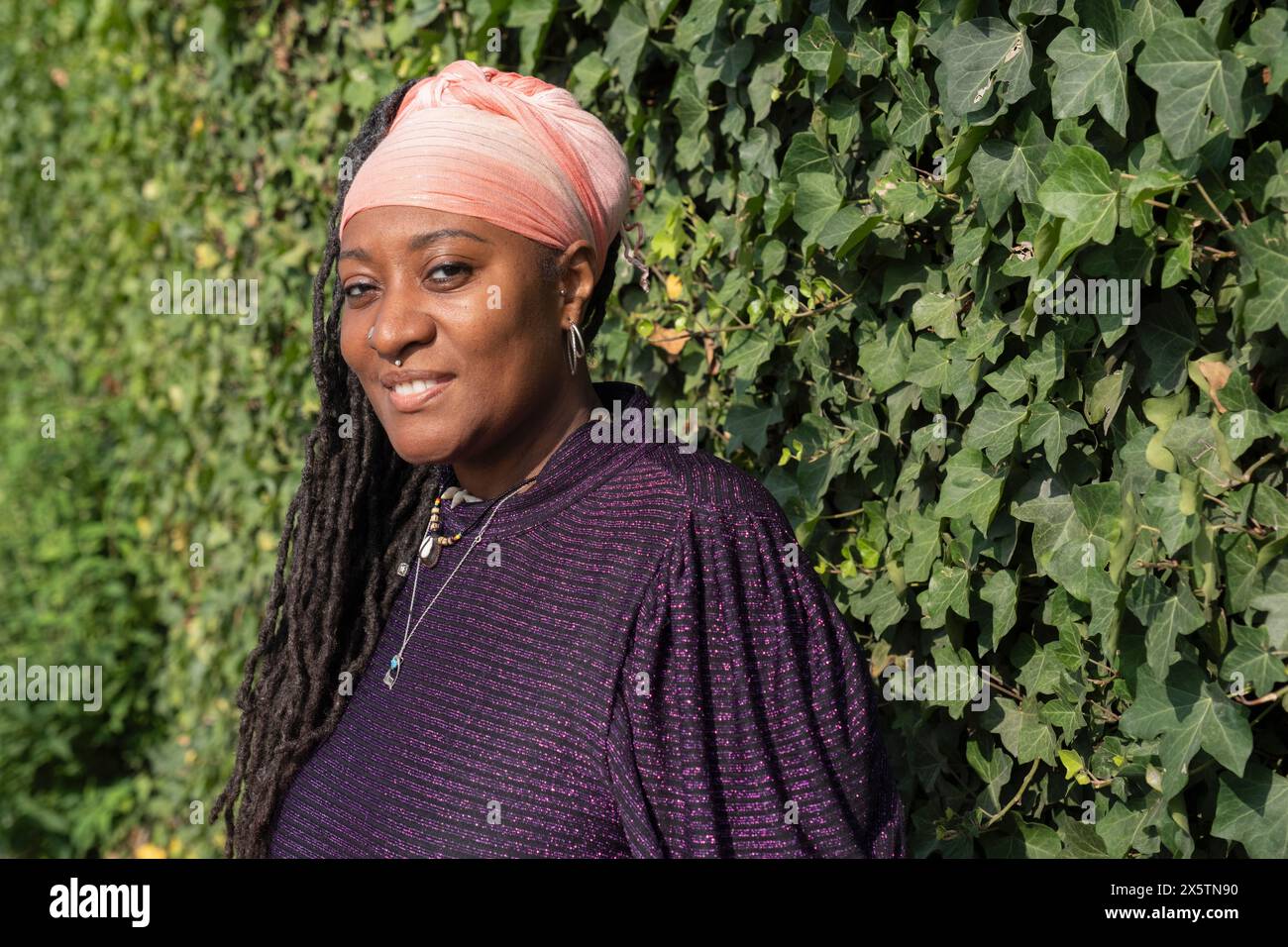 Porträt einer schönen Frau mit Dreadlocks vor der Efeuwand Stockfoto