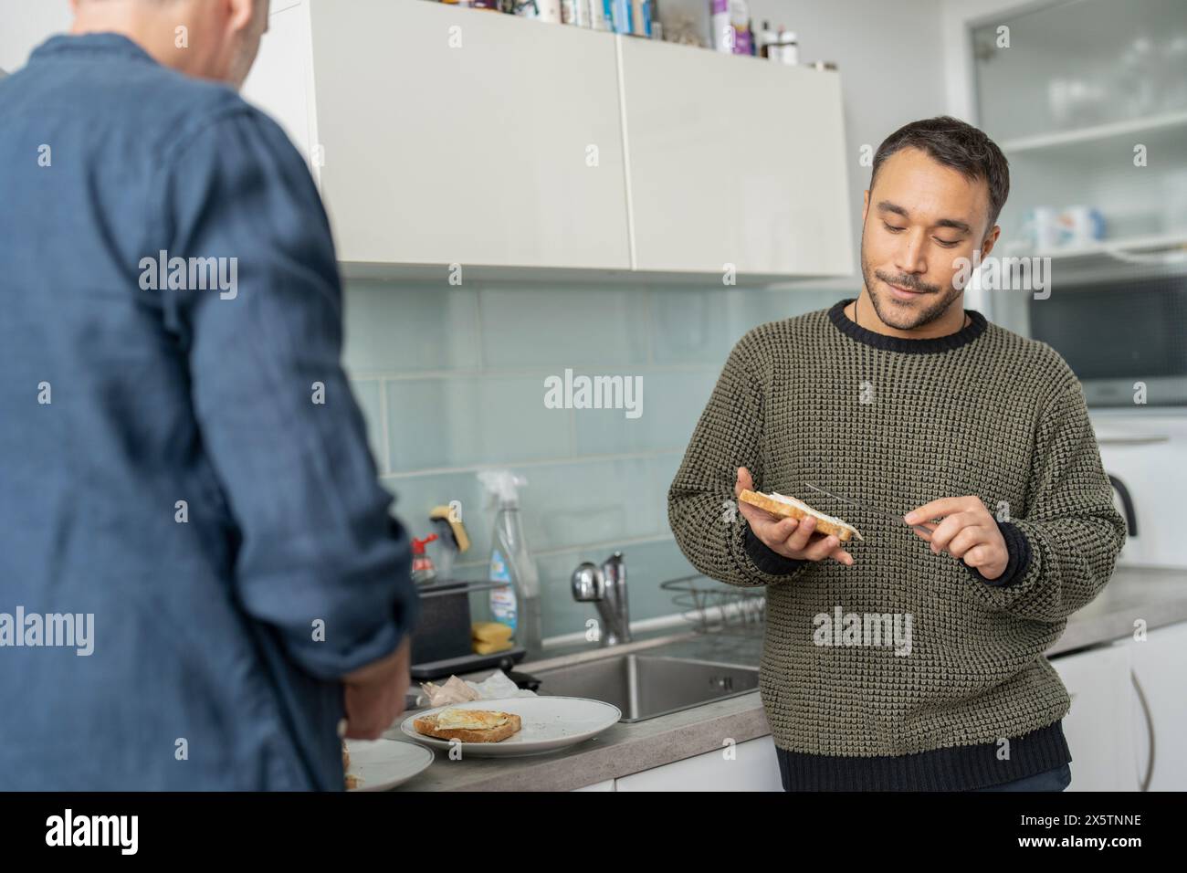 Männliches Paar bereitet zu Hause Frühstück vor Stockfoto