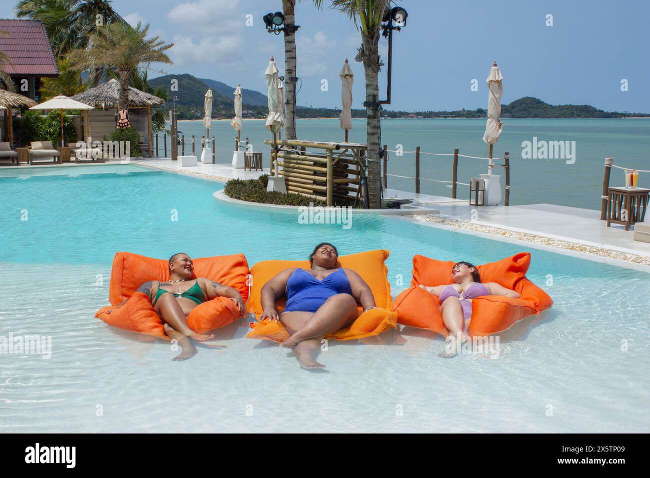 Gruppe von fröhlichen Frauen, die sich auf den Floßbooten im Swimmingpool entspannen Stockfoto