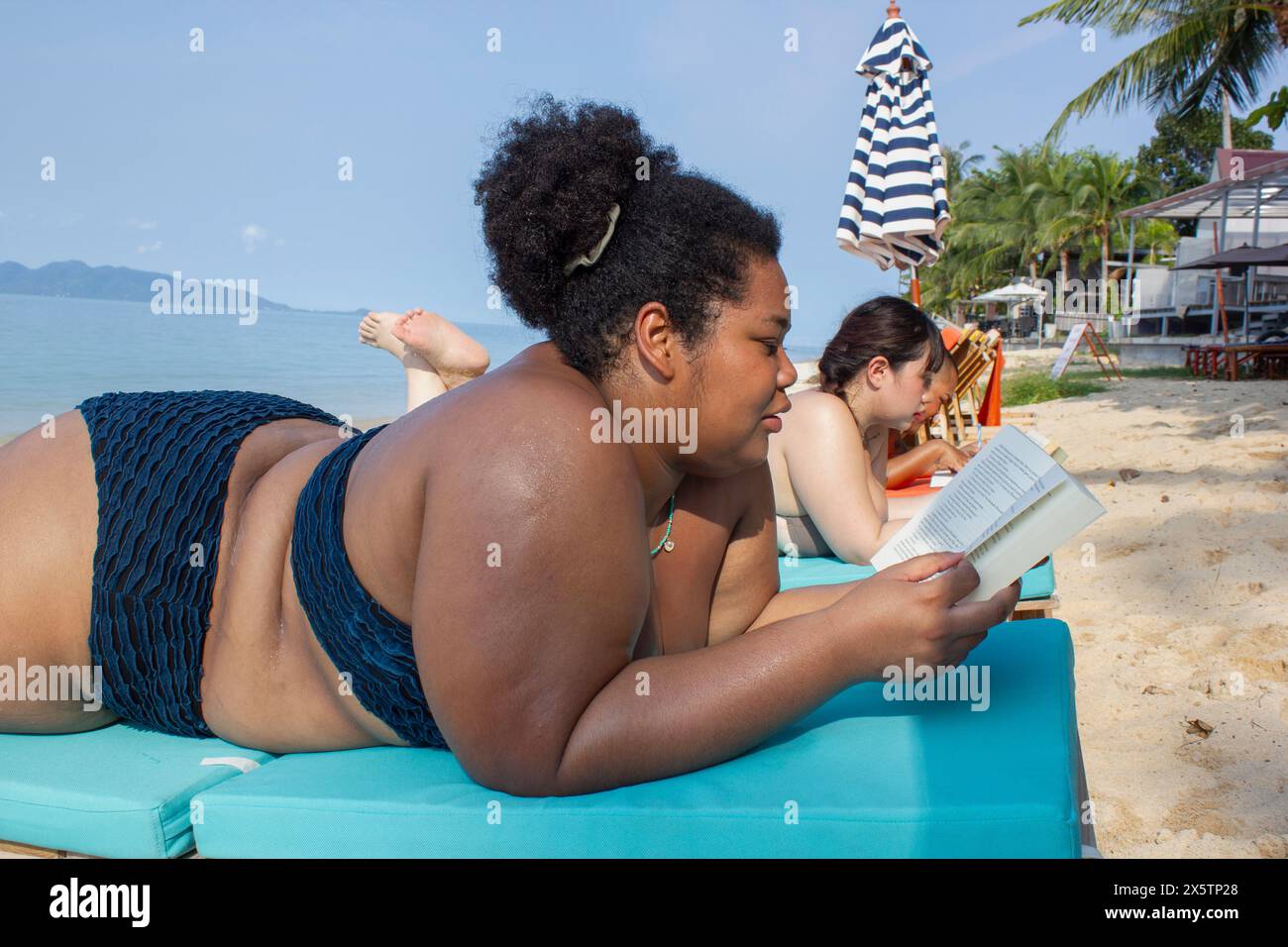 Eine Gruppe von Frauen, die sich am Strand entspannen und lesen Stockfoto