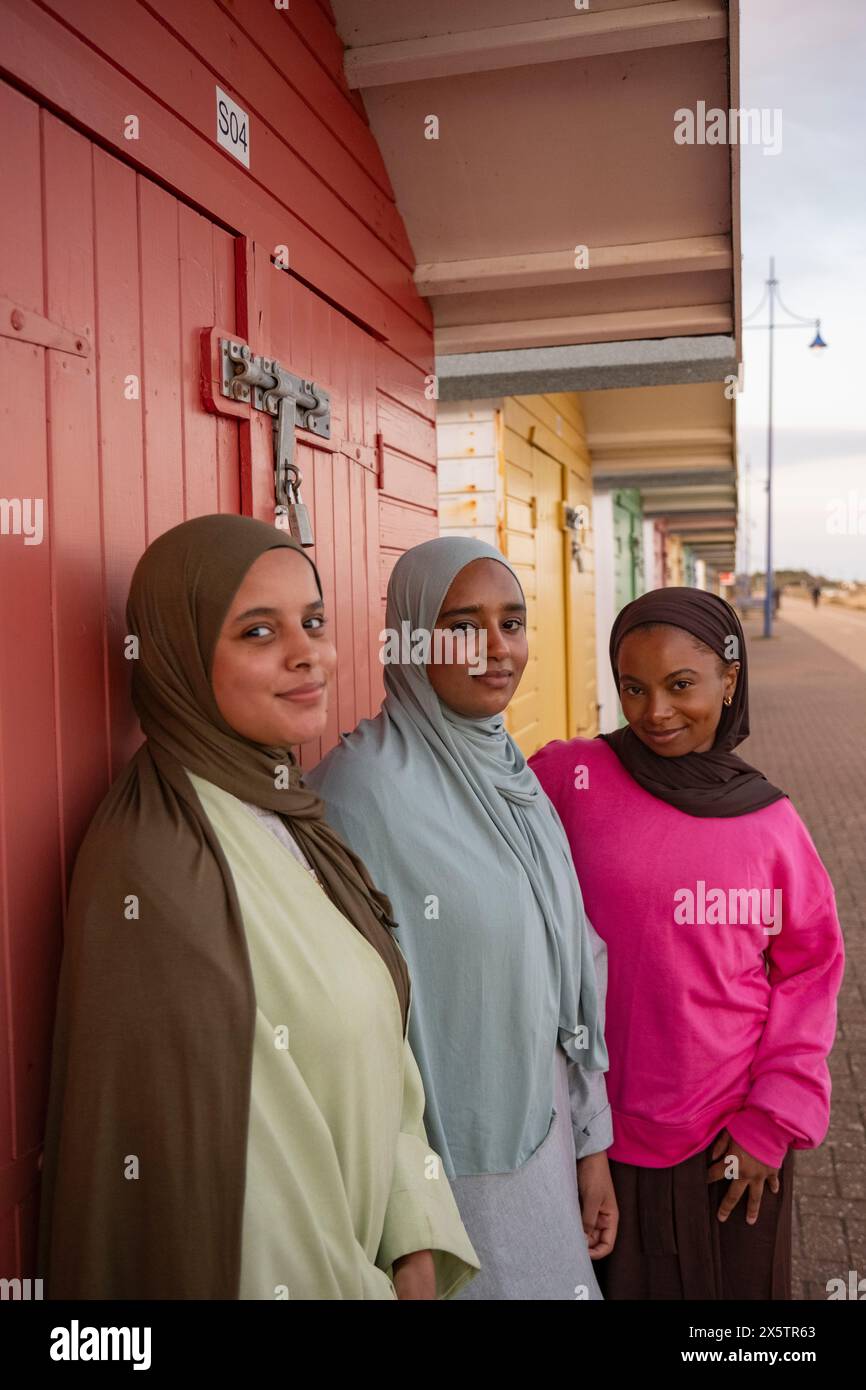 Porträt von drei muslimischen Freunden, die vor der roten Strandhütte stehen Stockfoto